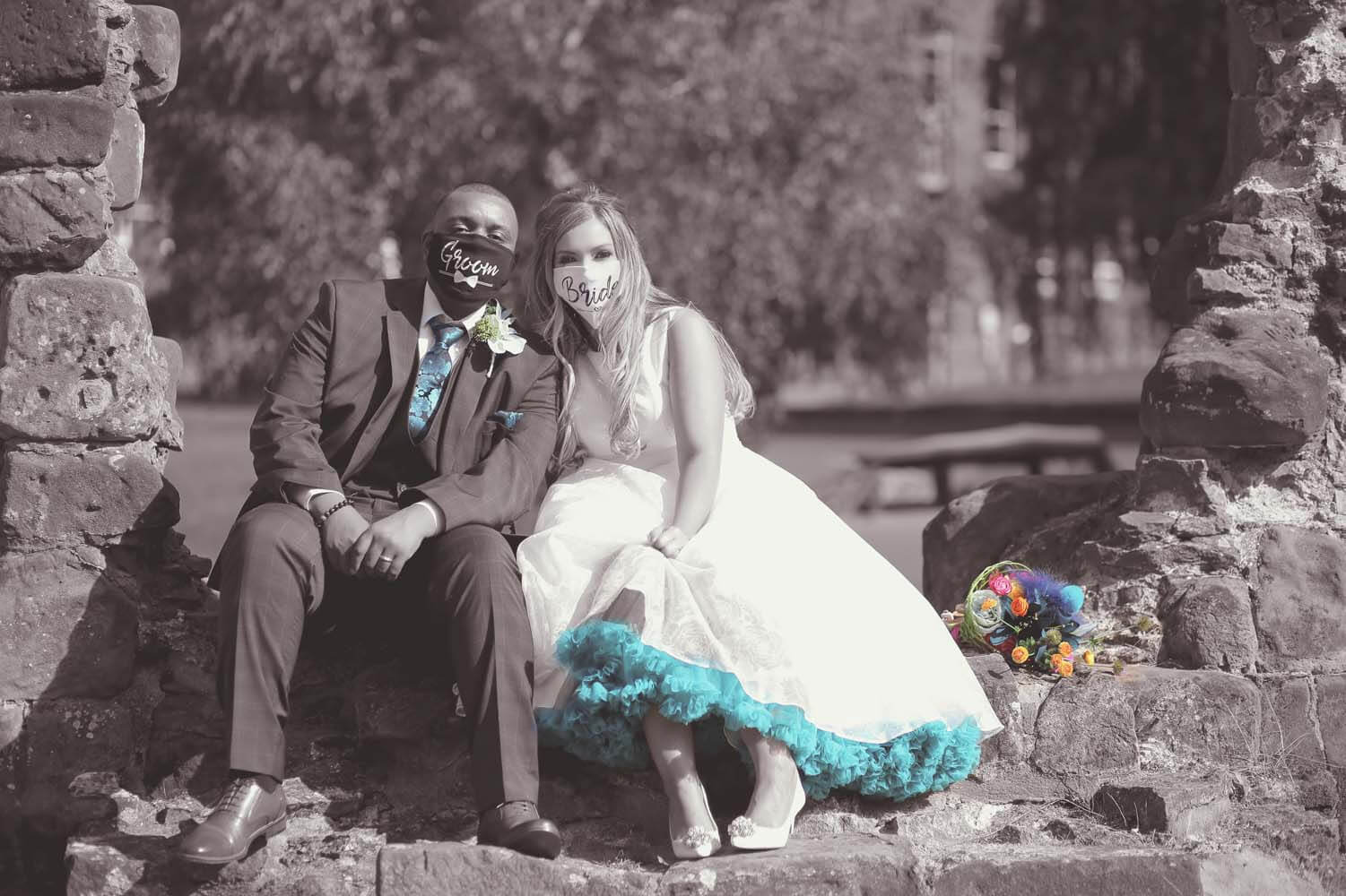 Bride and Groom sitting side by side wearing face masks.