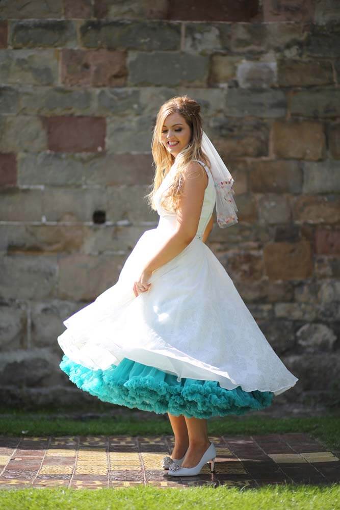 Bride wearing a 50's style tea length dress with teal underskirt.