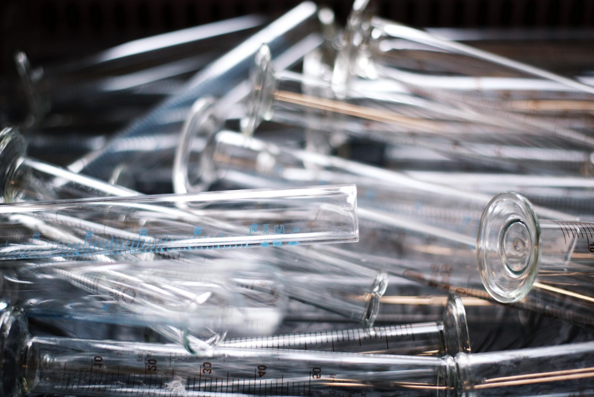 A closeup of a pile of empty, overturned testtubes on a flat surface.