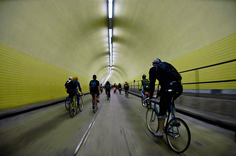group of people riding their bicycles in a tunnel