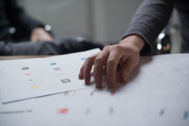 A hand rests on top of pages full of logo designs.