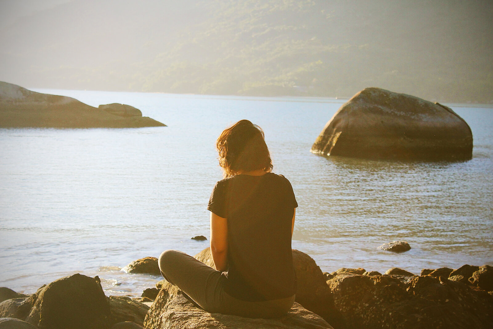 Woman meditating on a lake shore