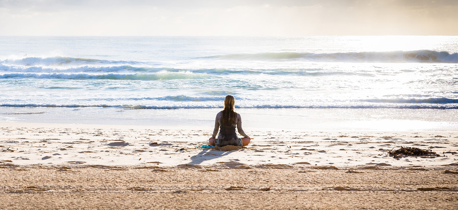 Woman meditating on a beach shore