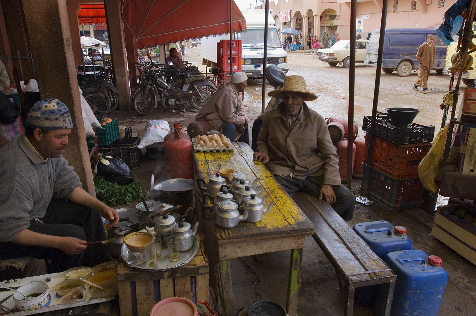 foto van twee mannen die aan een tafel op straat zitten, de ene maakt thee, in Marokko