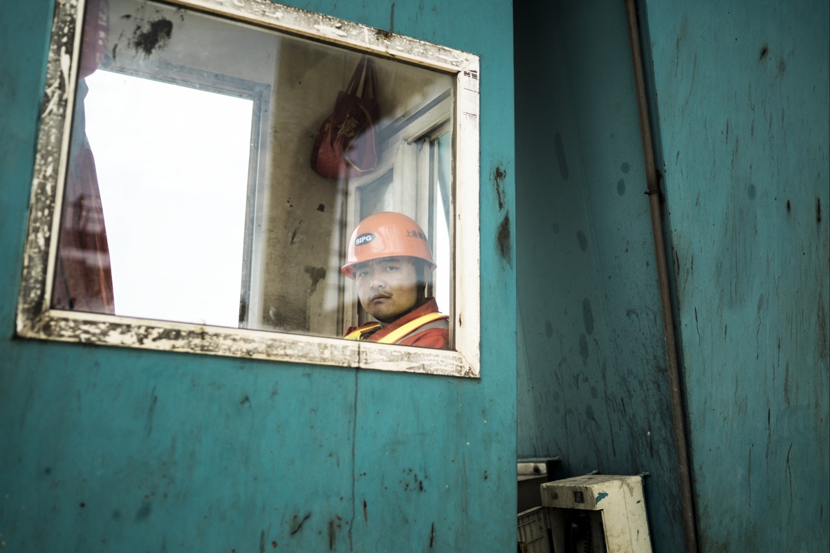 foto van Chinese werkman met helm achter raam in bouwkeet