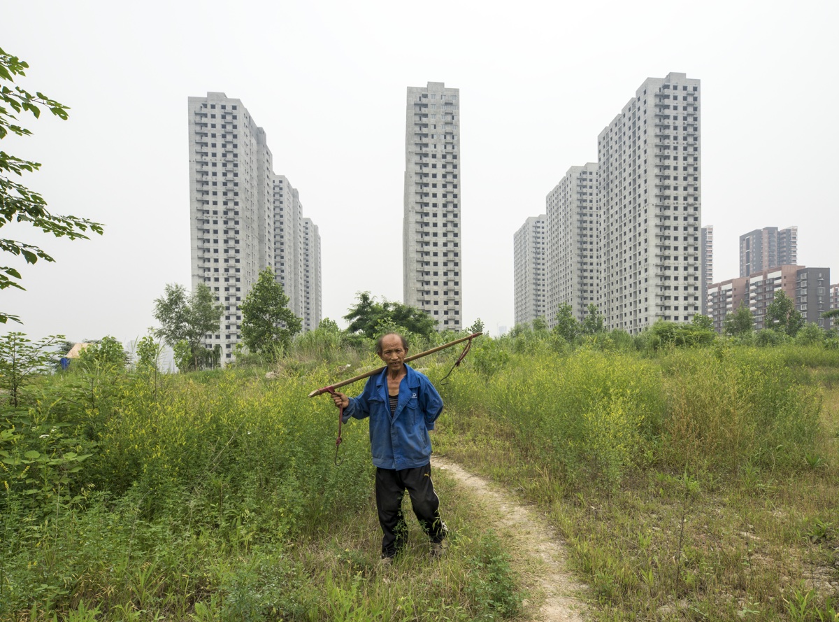 foto van flats van Shanghai met man met stok en touw op zijn rug ervoor
