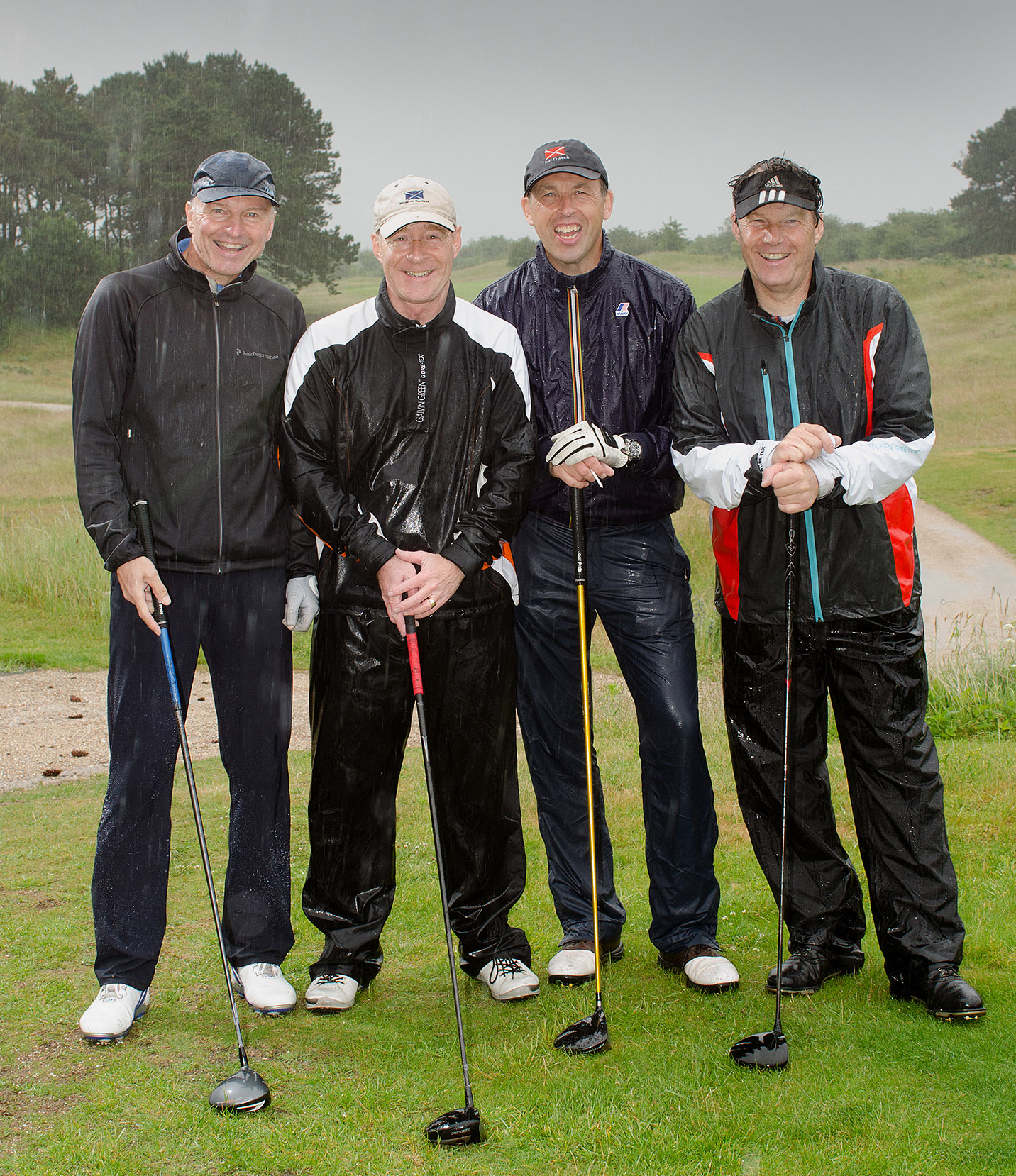 foto van vier mannen op de golfbaan in de regen lachend