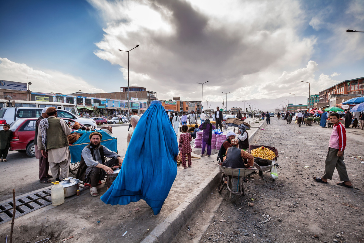 foto: Jeroen Swolfs. Afghanistan, Kabul, juni 2012. Een vrouw in burka haast zich door een straat in centrum Kabul waar allerhande producten op de stoep worden verkocht. Baghdad, Irak, december 2015. De duizend jaar oude boekenstraat Al-Mutanabbi werd in 2007 verwoest door een autobom. De straat werd herbouwd en de boekenmarkt trekt weer vele bezoekers.
