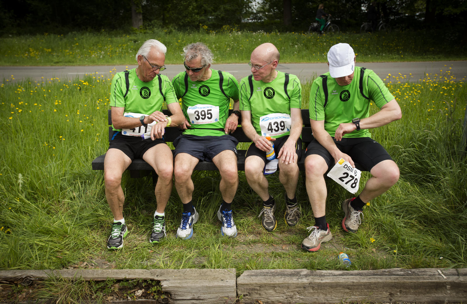 foto: © Bastiaan Heus - Treechloop, vier mannen zitten met nummers op buik op bankje in gras