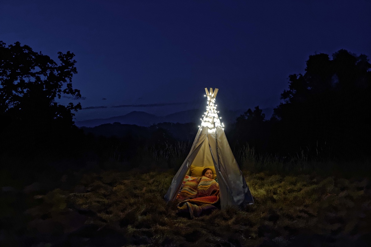 foto van tentje op een heide bij nacht met een kind erin