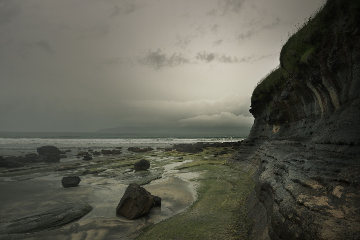 foto van kust met rotsen en grijze wolken