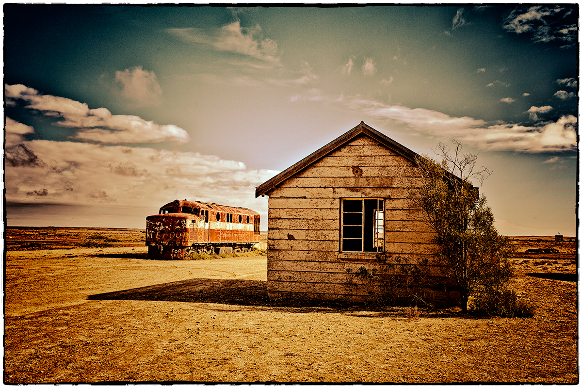 foto van een houten schuurtje en een oude stoomtrein in Australië in leeg landschap