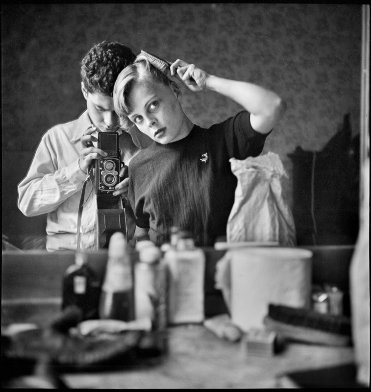zwartwit foto van Elliott Erwitt van vrouw die haar kamt in spiegel en fotograaf die erachter staat met camera