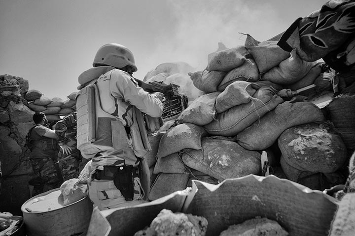 foto: Winnaar Zilveren Camera 2015: Eddy van Wessel | man met geweer achter blokkade me zandzakken in Sinjar