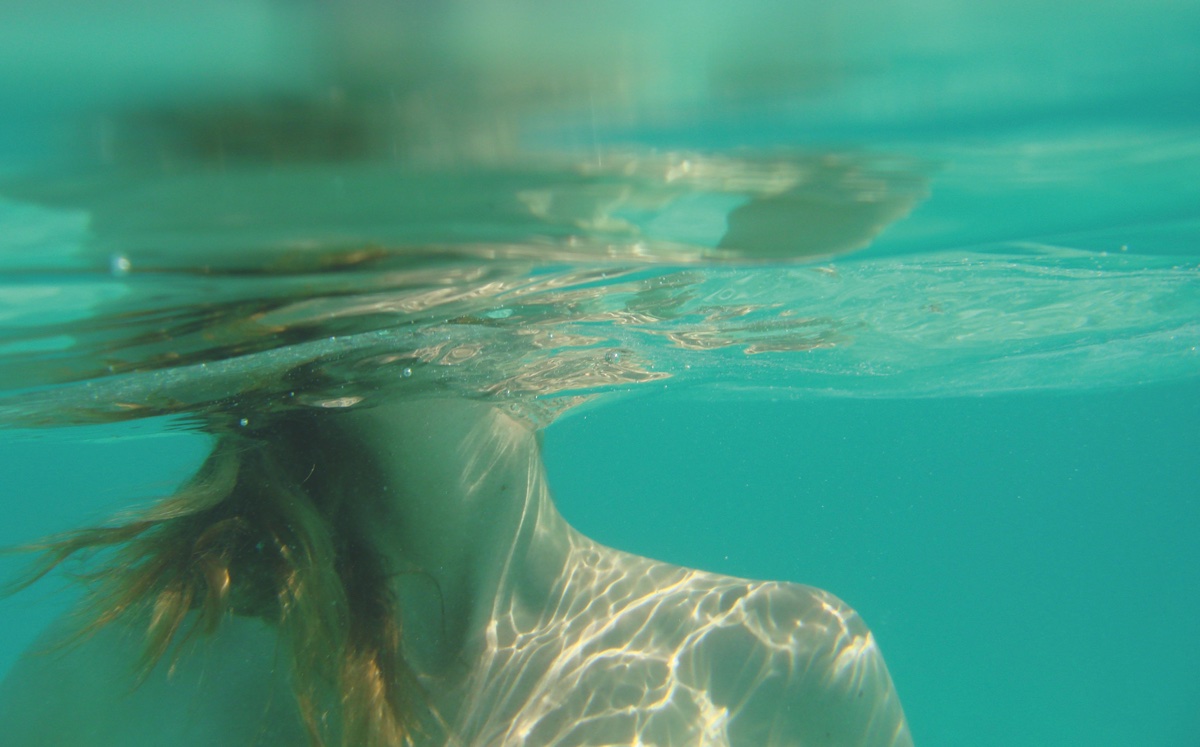 foto van een vrouw van kin tot borst onder water met lichtspiegelingen