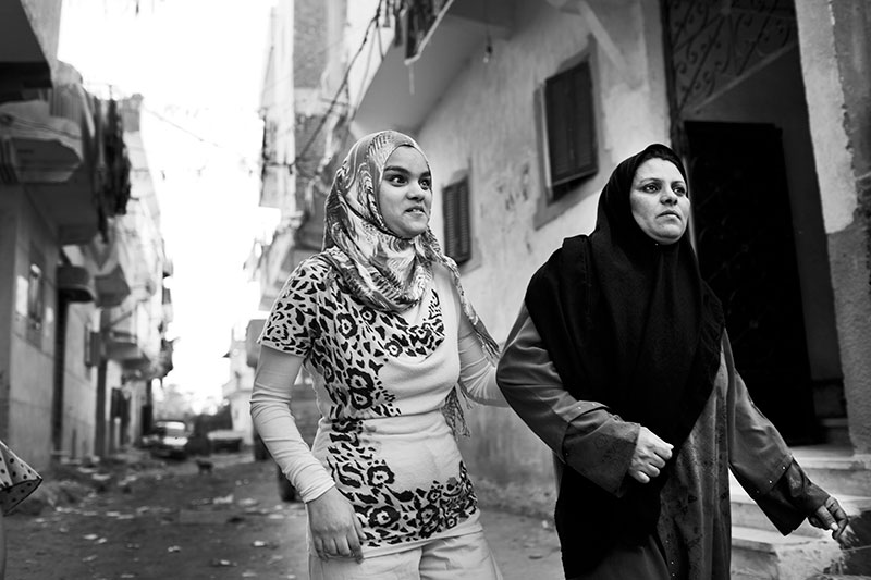 foto: Ahmed Hayman, Egypt, ftwee vrouwen met hoofddoek in steeg gearmd lopend, de ene is de dochter die blind is en houdt de moeder vast
