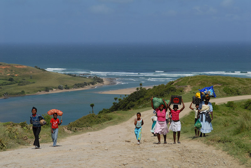 Zuid-Afrika - Wild Coast, vrouwen en kinderen lopen langs kust met goederen op hoofd