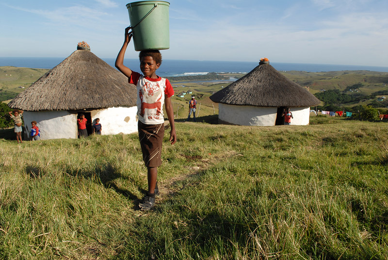 foto: Tom van der Leij zuid afrika, jongen met emmer op hoofd op heuvels bij zee, west coast