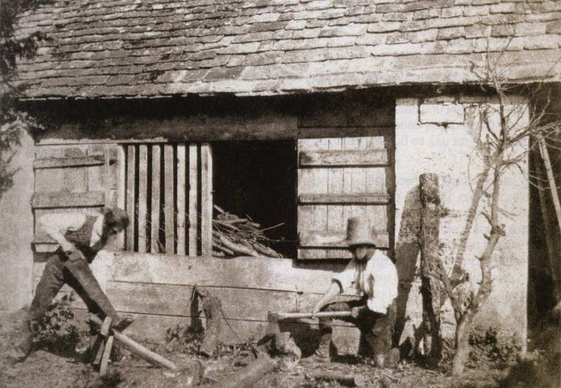 oude foto sepia schuur met twee mannen die hout zagen