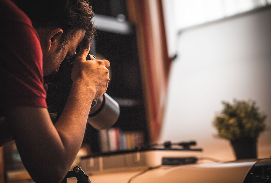 man maakt foto met camera met lange lens van zijn bureau