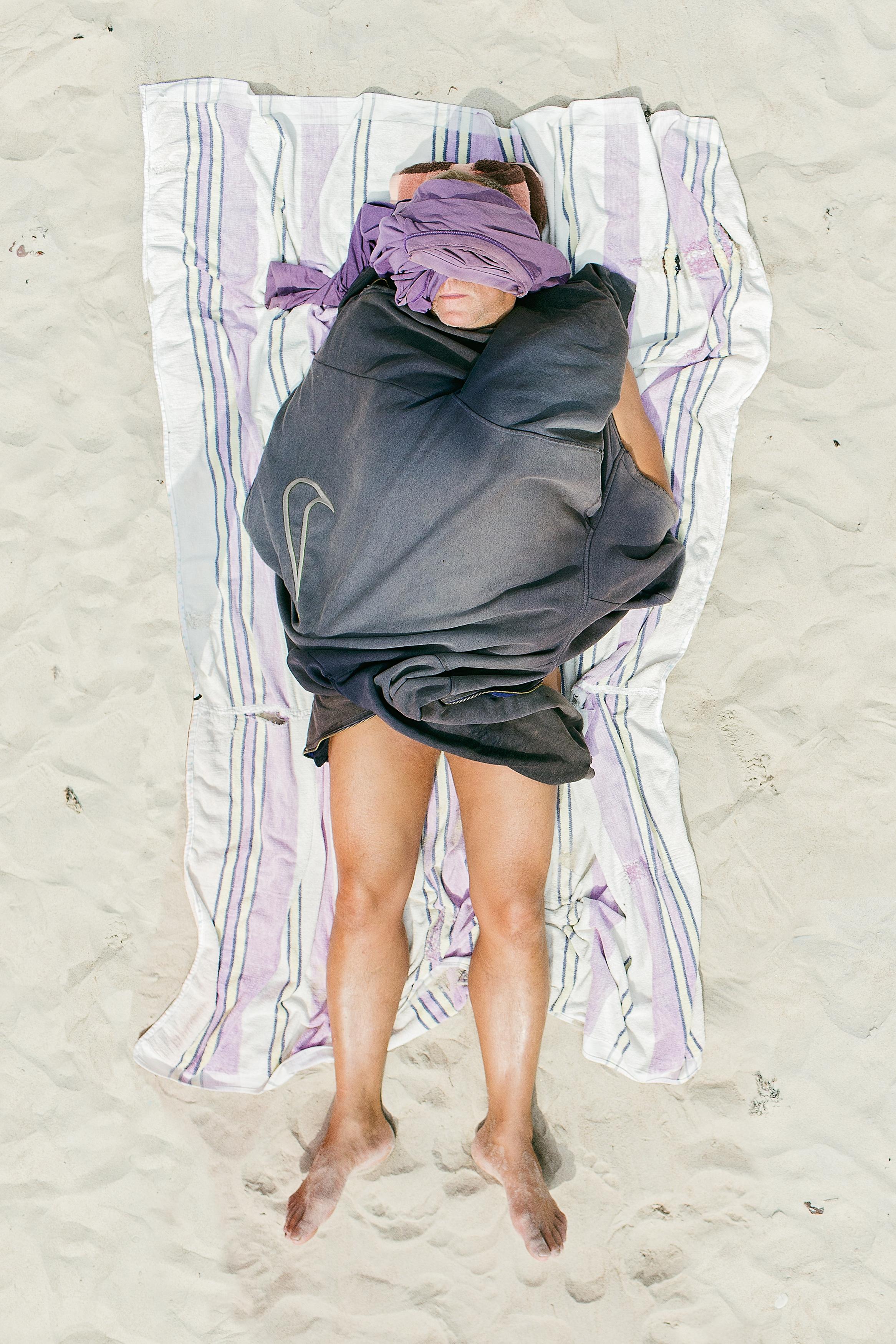man op strandlaken op zand