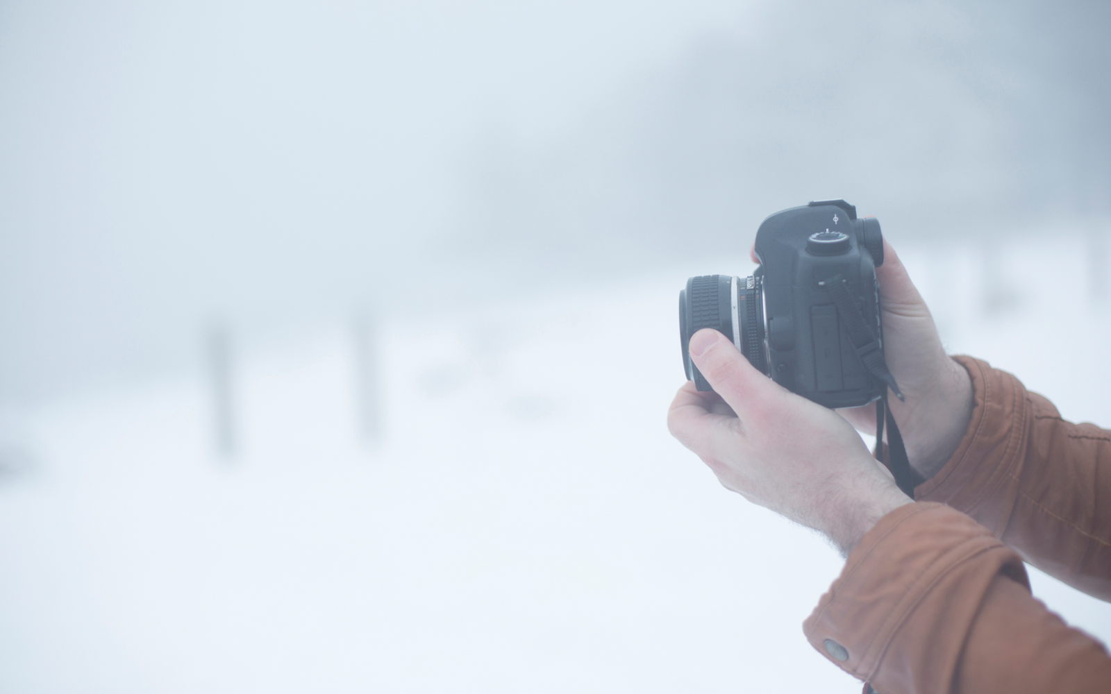 handen die camera vasthouden in sneeuw omgeving
