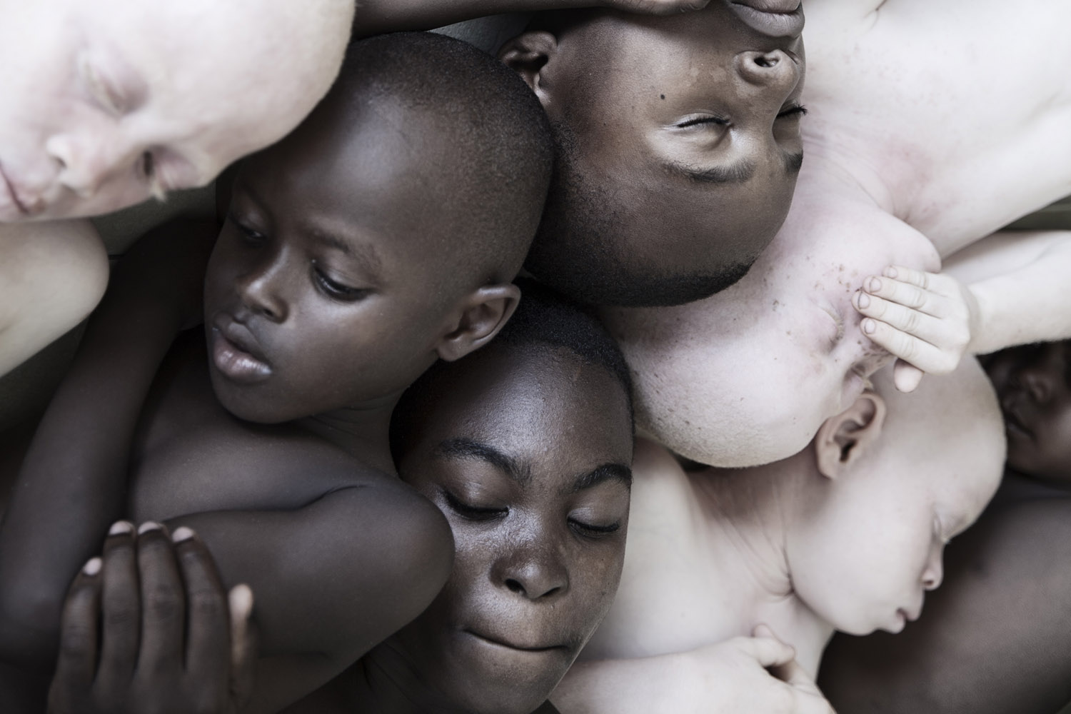 foto van hoofden van donkere en albino kinderen met ogen dicht door elkaar heen
