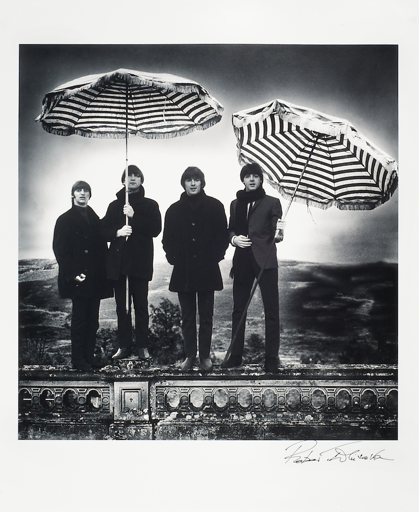 Foto van The Beatles met parasols als paraplu's dragend