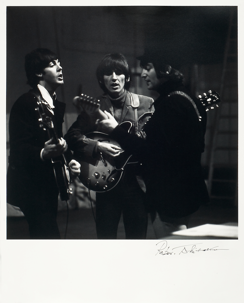 foto van drie van de vier van The Beatles zingend met gitaren