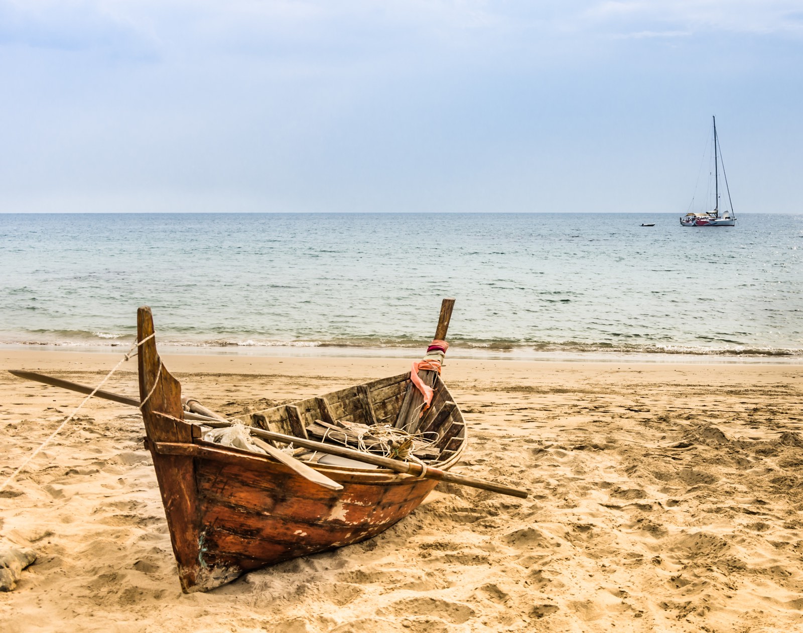 roeiboot op strand en op zee een zeilboot