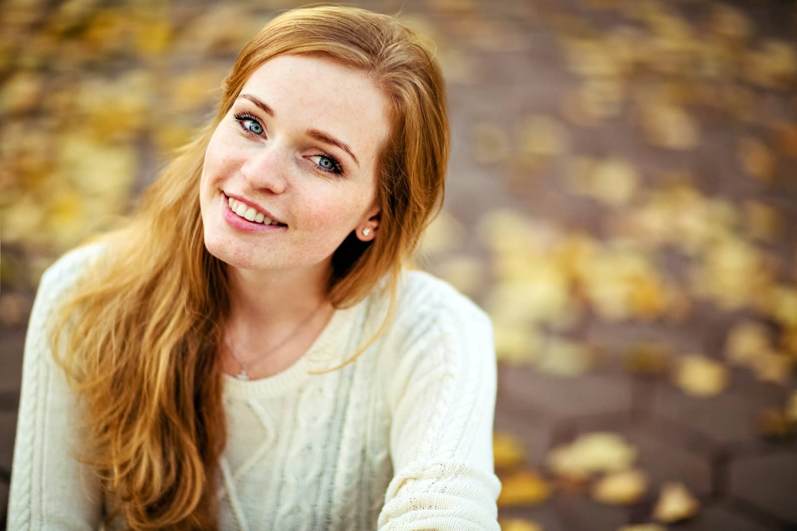 vrouw met rood haar lachend met vage herfstachtergrond