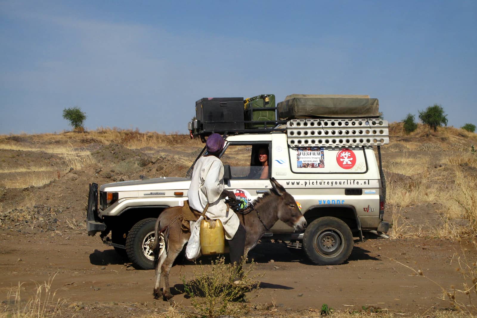 Ilvy Njiokiktjien in jeep in woestijn Sudan pratend tegen man op ezel
