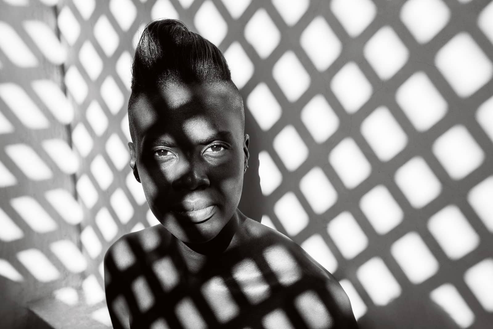 © Annelies Damen - Angalia: portret zwarte vrouw met licht dat door een hekwerk valt