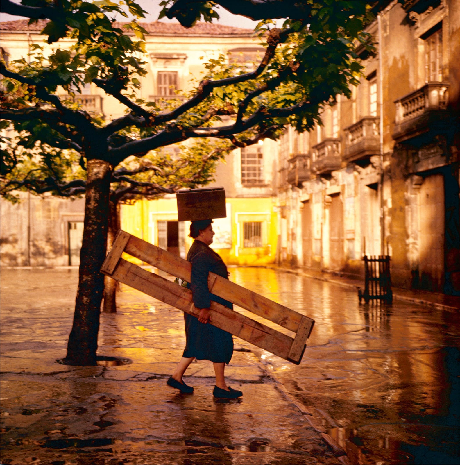 foto: © Carel Blazer/MAI - Spanje, 1956, vrouw met plank en kist op hoofd loopt over plein