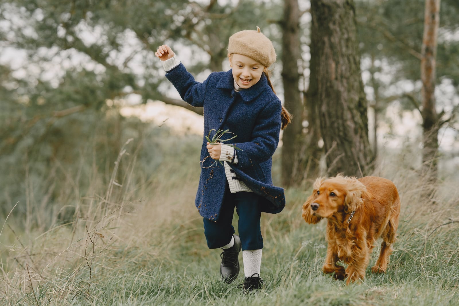 meisje met blauwe winterjas rent vrolijkmet hond in bos