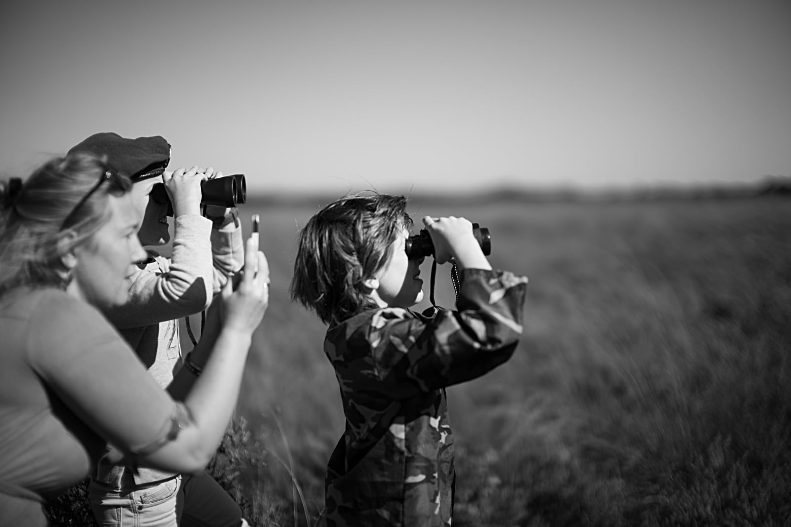 75 Jaar Vrijheid in Beeld - © Sacha de Boer - Airborne luchtlandingen herdenking op Ginkelse Heide, vrouw maakt foto's met mobiel en man en kind met verrekijker