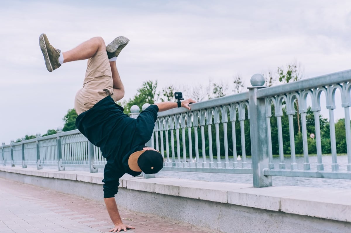 man doet breakdance bij brug met GoPro aan arm