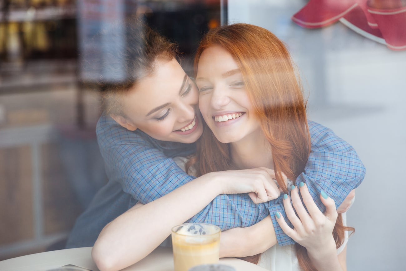 two-cute-lovely-happy-young-women-hugging-cafe
