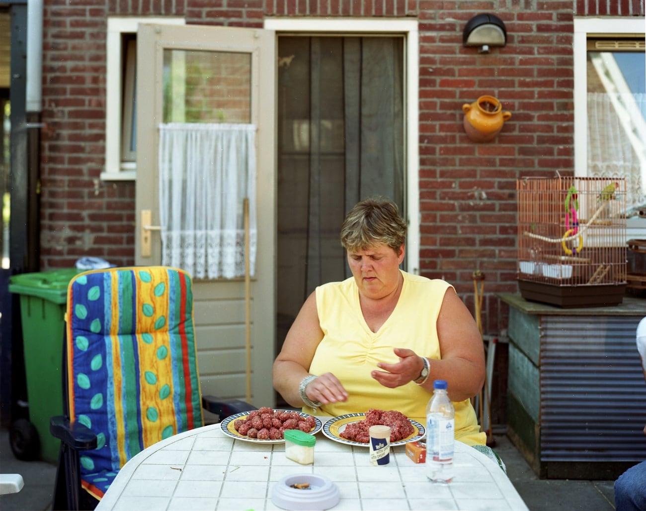 vrouw in tuinstoel in tuin die gehaktballen maakt uit Thuis in de stad expositie van Raymond Wouda