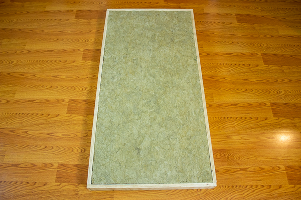 An image of insulation placed into the cavity of an acoustic panel's frame.