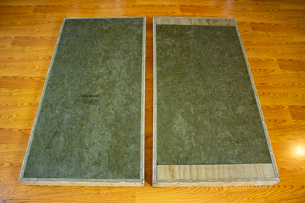 An image of fiberglass screen stapled to the front and back of two acoustic panel frames containing insulation.