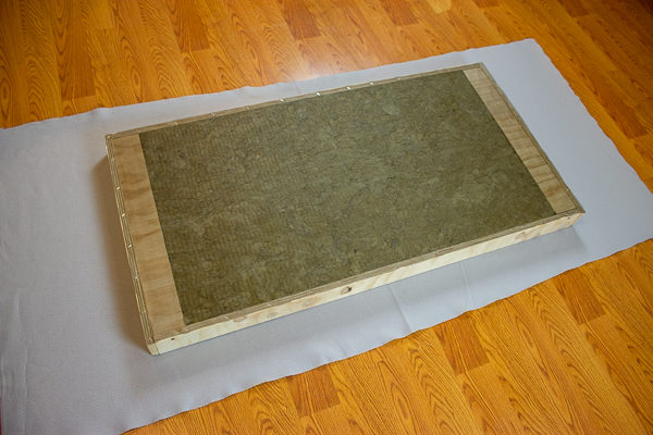 An image of an acoustic panel laying face down on a piece of felt.