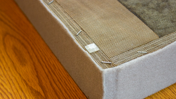 A close up view of a furniture bumper stuck onto the back of an acoustic panel.