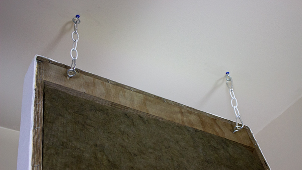 An image of an acoustic panel hanging from two suspension assemblies.