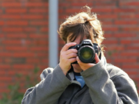 man taking picture facing computer screen
