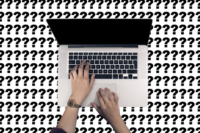 person typing on a computer with question mark background