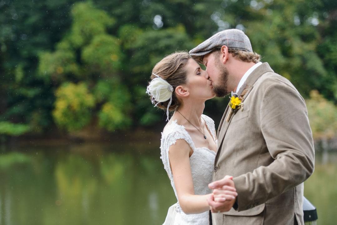 a bride and groom kiss in front of a green pond at wye island nrma