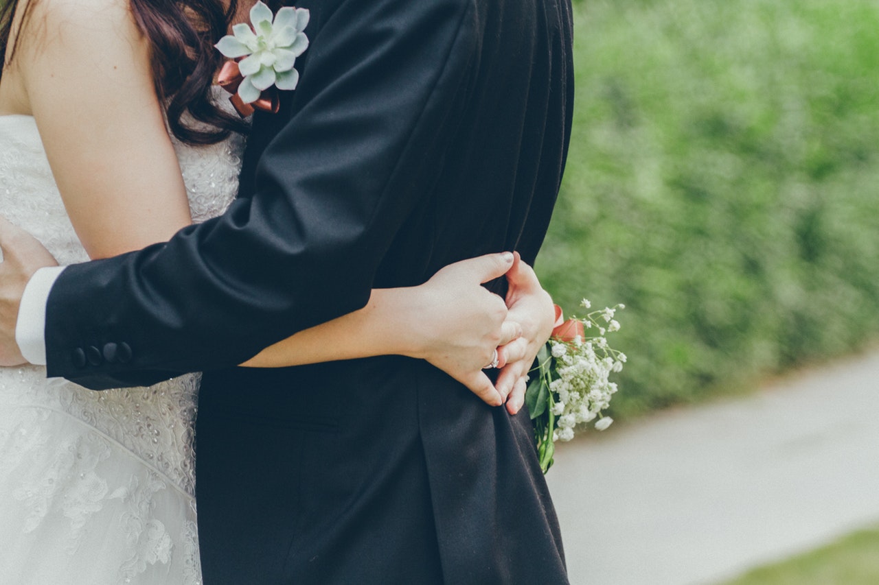 a bride and groom with their arms wrapped around one another