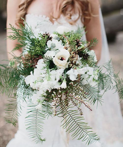 A rustic wedding bouquet with ferns, pieris, pinecones, and evergreens | Brides.com
