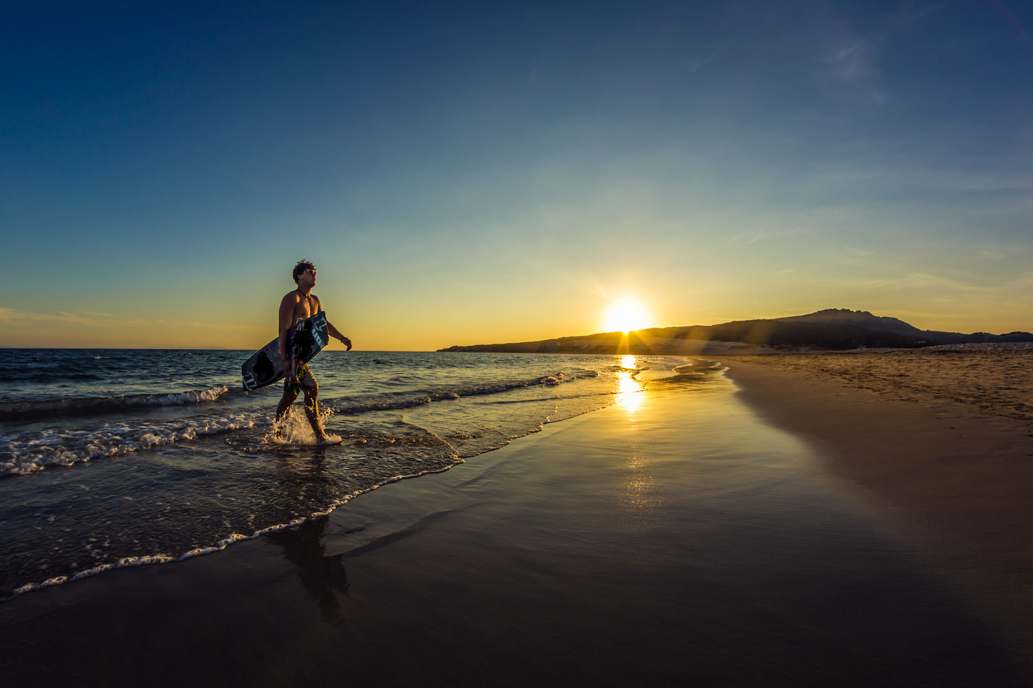 lone beach in tarifa with kiteboarder walking out of the water
